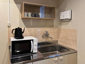 a kitchen with a microwave and a sink at Kimono Hotel Himeji 着物宿 in Himeji