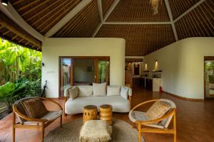 a living room with a white couch and chairs at Flor Villa by Betterplace in Dalung
