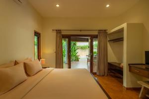 a bedroom with a large bed and a television at Flor Villa by Betterplace in Dalung