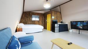 a bedroom with a bed and a tv and a couch at Gyeongju raon glamping in Samgong