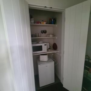 a small kitchen with a microwave and a toilet at Sandspit Hideaway in Sandspit