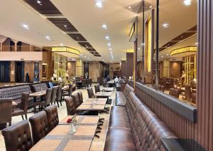 a restaurant with long tables and leather seats at Grand Elite Hotel Pekanbaru in Pekanbaru