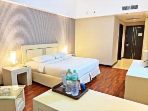 a hotel room with a bed and two bottles on a tray at Grand Elite Hotel Pekanbaru in Pekanbaru