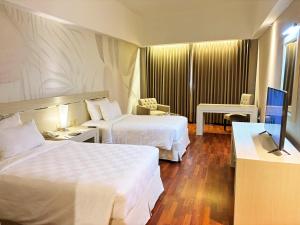 a hotel room with two beds and a television at Grand Elite Hotel Pekanbaru in Pekanbaru