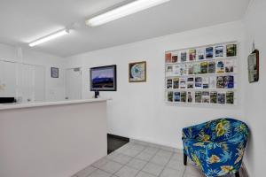 a white room with a blue chair and posters on the wall at Avon Motel in Hawera