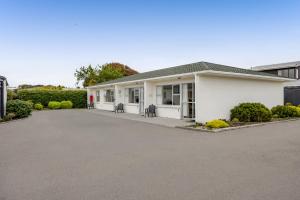 a white house with a driveway in front of it at Avon Motel in Hawera