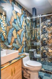 a bathroom with a toilet and a mural of leaves at El Camino De Diego in Otavalo +35 photos