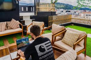 a man sitting in a chair with a laptop on a balcony at El Camino De Diego in Otavalo