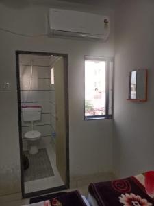 a bathroom with a toilet and a window and a mirror at Keshav femely banglow in Dwarka