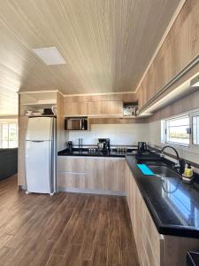 a kitchen with a white refrigerator and wooden cabinets at Chacra Piriápolis in Piriápolis
