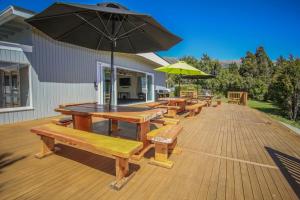 a row of picnic tables with an umbrella on a deck at Rotoiti Lodge in Saint Arnaud
