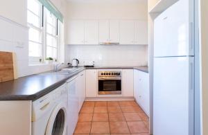 a kitchen with white cabinets and a dishwasher at Beach Belle Mornington in Mornington