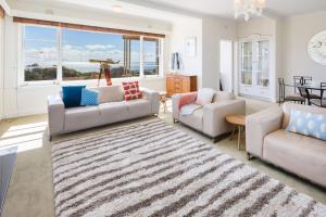 a living room with two couches and a rug at Beach Belle Mornington in Mornington