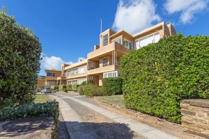 an apartment building with bushes in front of a street at Beach Belle Mornington in Mornington