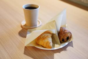 a plate with two croissants and a cup of coffee at ファーストキャビン松江 in Matsue