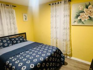 ein Schlafzimmer mit einem Bett und einer gelben Wand mit Vorhängen in der Unterkunft Private 2BR Home Near APG Fast-Entire House in Aberdeen