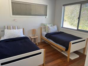 a bedroom with two beds and a window at Forest Tangle Retreat, Two Bedroom in Diddillibah