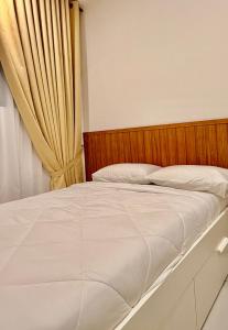 a bed with a wooden headboard next to a curtain at NeoSkyhigh Suites in Batu Kawan