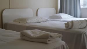 two beds with white sheets and pillows in a room at Hotel Joia in Cascavel