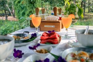 a table with plates of food and glasses of orange juice at Baancherda in Ban Nong Hu