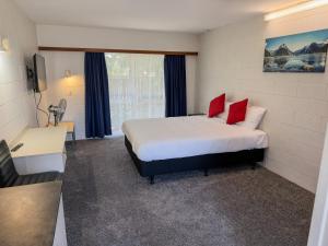 a room with a bed with two red pillows at Midway Pacifica Lodge in Lower Hutt