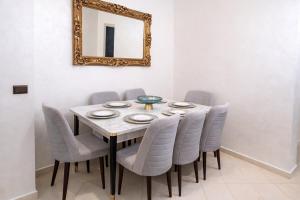a dining room table with gray chairs and a mirror at Spacious Family-Friendly Apartment in Temara