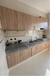 a kitchen with a sink and wooden cabinets at Spacious Family-Friendly Apartment in Temara +1 photo