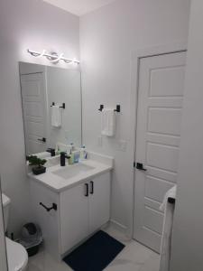 a white bathroom with a sink and a mirror at Mayfair Suite in Airdrie
