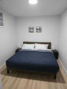 a bed in a white room with a blue blanket at Mayfair Suite in Airdrie