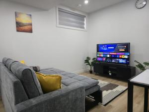 a living room with a couch and a flat screen tv at Mayfair Suite in Airdrie