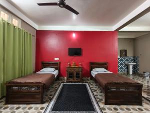two beds in a room with a red wall at Prashaanti in Guwahati