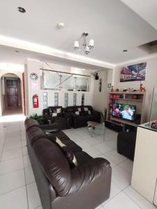 a living room with a leather couch and a television at HOSTAL REAL CERRILLOS in Moquegua