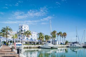 a marina with boats and a building with a clock tower at CP - Modern Beachside Apartment in Estepona in Estepona