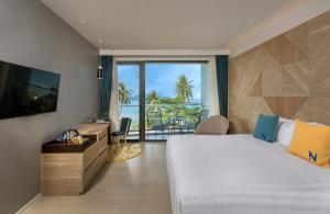 a hotel room with a large bed and a television at The Nature Phuket in Patong Beach