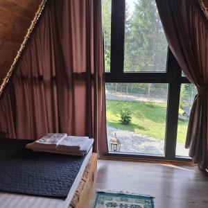 a bed in a room with a large window at Cabana Armonia Naturii in Avrig