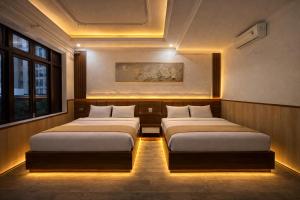 two beds sitting in a room with lights at Yen Binh Hotel in Hòa Ðình
