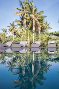 a reflection of palm trees in the water at a resort at Junjungan Serenity Villas & Spa in Ubud