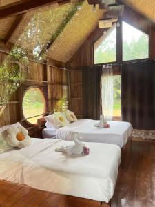 a room with three beds with white sheets and windows at Baanraipoonwana Baanwanason in Ban Nong Hu