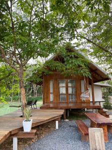 a wooden cabin with a bench and a tree at Baanraipoonwana Baanwanason in Ban Nong Hu +10 photos