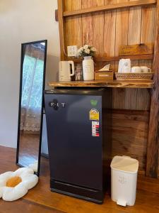a small black refrigerator in a room with a shelf at Baanraipoonwana Baanwanason in Ban Nong Hu