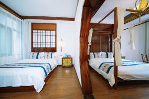 two beds in a room with white walls and wooden floors at 茶颜悦舍 in Fenghuang County