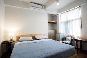 a bedroom with a bed with a blue comforter and a window at Mountain View GuesthouseChiangmai in Chiang Mai
