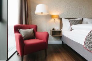 a bedroom with a red chair and a bed at Chester Hotel Heidelberg in Heidelberg