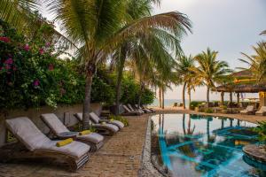 a resort pool with lounge chairs and palm trees at Sailing Club Resort Mui Ne in Mui Ne