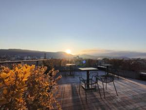 a deck with tables and chairs and the sunset at Shizuru 鴨川 ""旧SGR鴨川"" in Kyoto