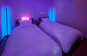 two beds in a room with pink and blue lights at THE BOXY AWAJI in Awaji +21 photos