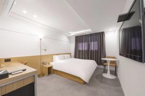 ein Hotelzimmer mit einem weißen Bett und einem Schreibtisch in der Unterkunft Busan Hauendae Ark Blue Hotel in Busan