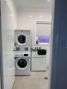 a white laundry room with a washer and dryer at Ocean Breeze Cottage in Umina