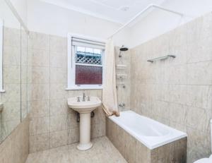 a bathroom with a sink and a toilet and a bath tub at Ocean Breeze Cottage in Umina +11 photos