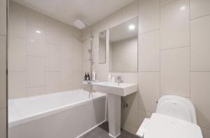 ein weißes Badezimmer mit Badewanne, Waschbecken und Toilette in der Unterkunft Busan Hauendae Ark Blue Hotel in Busan